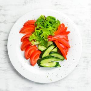 Ассорти из овощей в тарелке нарезка свежих овощей огурец помидор перец меню ресторана вид сверху